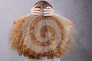 A girl gathering her thick wavy natural hair with her hands