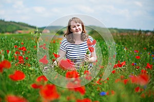 Girl gathering poppies on the field in Auvergne