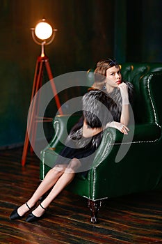 Girl in a Gatsby-style sitting in a luxurious armchair in gloves