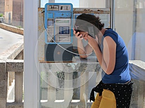 Girl gesturing sad on a public payphone cabin