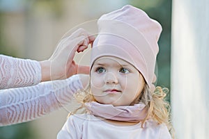 Girl get hat put on head by female hands