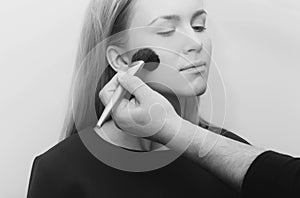 Girl getting powder on face with makeup brush in hand