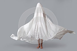 A girl in a Ghost costume on a gray background in the Studio. Halloween