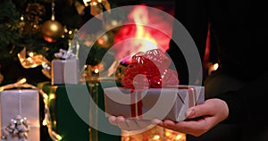 Girl with gift under Christmas tree near fireplace