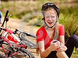 Girl girl fell off bike. Cyclist girl keeps self for bruised knee.