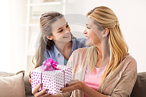 Girl giving birthday present to mother at home