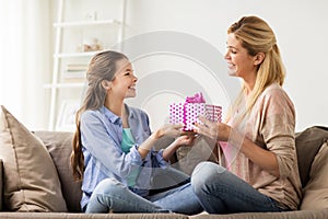 Girl giving birthday present to mother at home