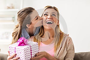 Girl giving birthday present to mother at home