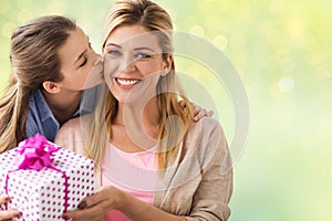 Girl giving birthday present to mother over lights