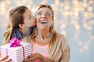 Girl giving birthday present to mother over lights