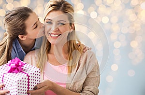 Girl giving birthday present to mother over lights