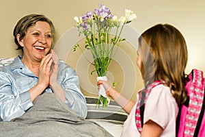 Girl giving bouquet of flowers to grandmother