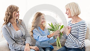 Girl giving bouquet of tulips to her grandmother