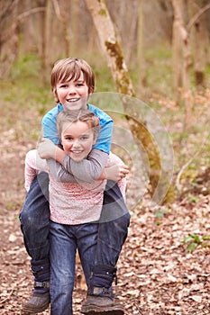 Girl Giving Boy Piggyback Ride On Countryside Walk