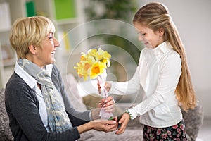 Girl giving a bunch of flowers to her grandmother