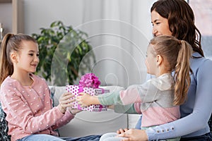 girl giving present to younger sister at home