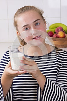 Girl with glass of milk in kitchen