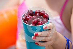 Girl with a glass of ripe cherry