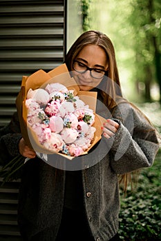girl with glasses and gray jacket rejoices at bouquet of pink roses.