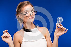 Girl in glasses with a light bulb in his hands