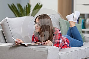 Girl in glasses listening music from smartphone with headphones in the living room at home.