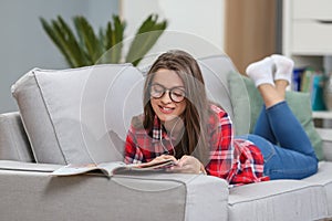 Girl in glasses listening music from smartphone with headphones in the living room at home.