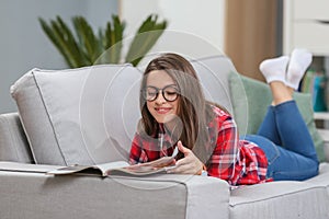 Girl in glasses listening music from smartphone with headphones in the living room at home.