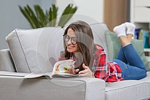 Girl in glasses listening music from smartphone with headphones in the living room at home.