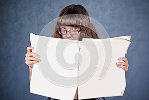 Girl in glasses looking over newspaper