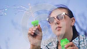 Girl with glasses outdoors blow bubbles