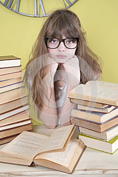 Girl in glasses sitting behind books.