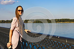 Girl with glasses standing on the waterfront at the fence