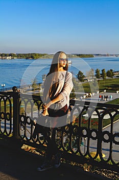 Girl with glasses standing on the waterfront at the fence