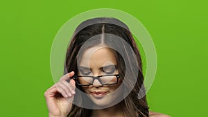 Girl in glasses starts to flirt and sexually remove glasses. Green screen. Close up