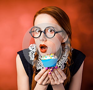 Girl in glasses with two pigtails holding cupcake