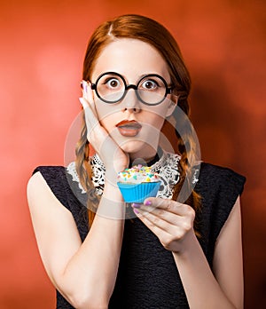 Girl in glasses with two pigtails holding cupcake