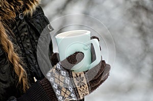 Girl in gloves holding cup of tea, white snowy background