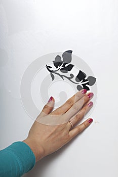 The girl glues the cut out elements from self-adhesive paper, to mask the defects of the white door.