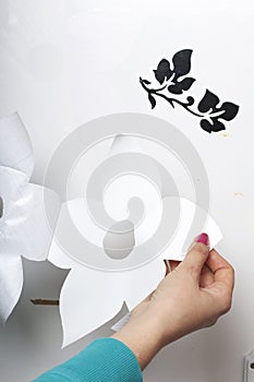 The girl glues the cut out elements from self-adhesive paper, to mask the defects of the white door.