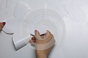 The girl glues the cut out elements from self-adhesive paper, to mask the defects of the white door.