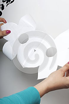 The girl glues the cut out elements from self-adhesive paper, to mask the defects of the white door.