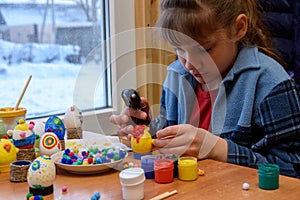 A girl glues a decorative element to a craft with a glue gun