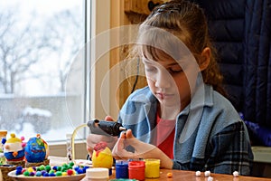 A girl glues a decorative element to crafts with a glue gun