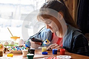 A girl glues elements to crafts with a glue gun