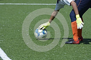 Girl goalkeeper placing the soccer ball to kick it far in the football field