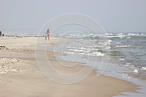 girl goes next to a bicycle along the beach against the background of the sea