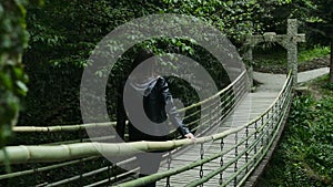 Girl goes on a suspension bridge in a dense forest