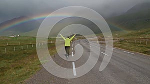 A girl goes to the rainbow along the road