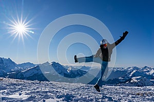 Girl with goggles and helmet is leaping midair in winter