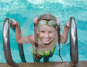 Girl in goggles leaves pool.